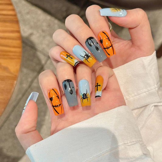 Dramatic Halloween pumpkin spider coffin long press-on nails with vibrant orange pumpkins, black spiders, and gothic cross designs