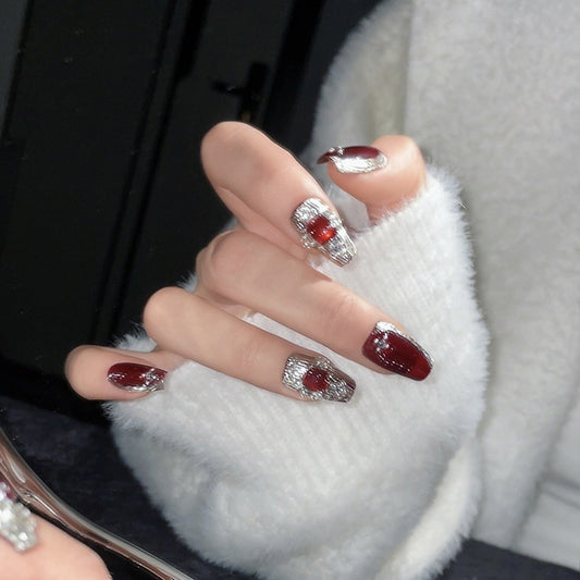 Elegant coffin-shaped short nails featuring rich red tones, chrome silver elements & crystal embellishments for glamour