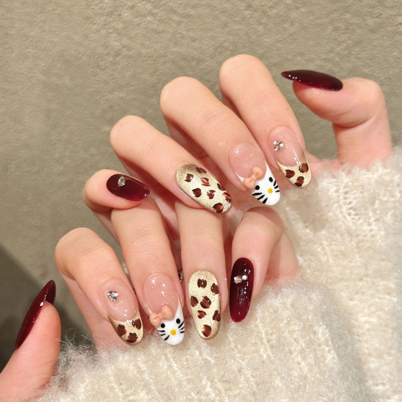 Adorable almond nails with 3D Hello Kitty, leopard print, burgundy gloss & crystals - perfect for kawaii kitty charm & playful style