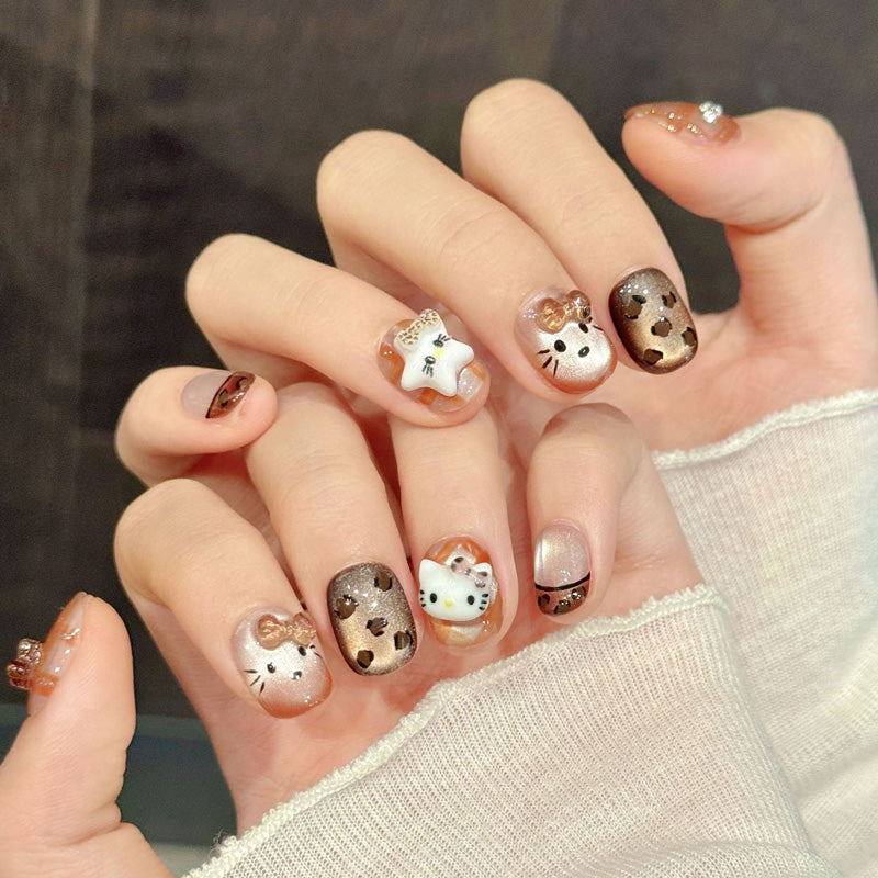 Adorable squoval short nails with Hello Kitty, bear faces, leopard print & gold bows - perfect for kawaii kitty bear leopard charm & playful style