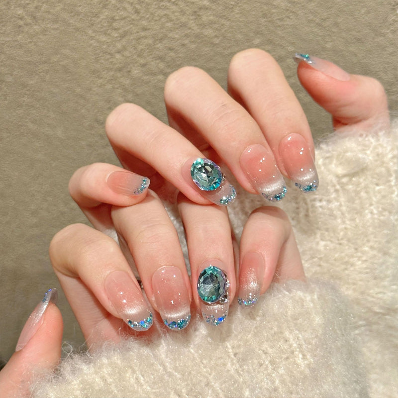 Elegant oval nails with ocean blue crystal, silver glitter, peach gradient & shell accents - perfect for ocean blue crystal glitter gradient mermaid elegance