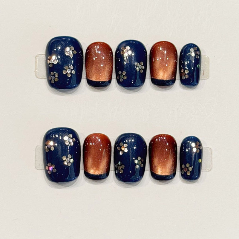 Elegant short squoval press-ons in midnight blue with hand-painted cherry blossoms, copper gradient & rhinestones - nature-inspired art