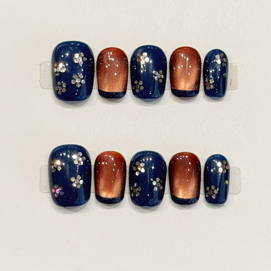 Elegant short squoval press-ons in midnight blue with hand-painted cherry blossoms, copper gradient & rhinestones - nature-inspired art