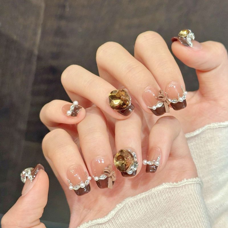 Elegant squoval short nails with brown French tips, crystal accents, bow & pearl chain - perfect for brown French crystal bow timeless elegance