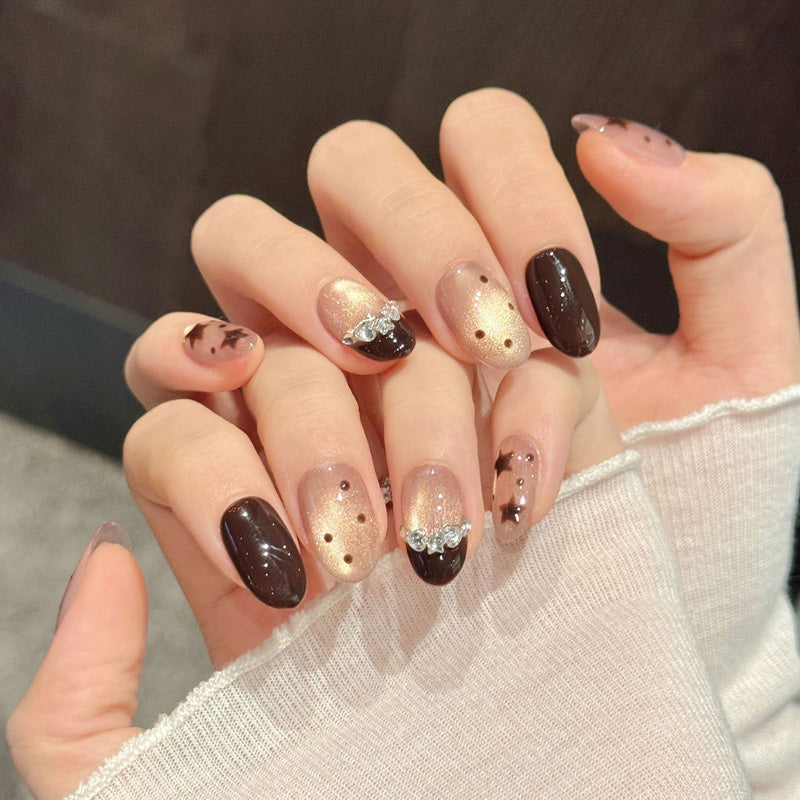 Enchanting oval nails in cosmic brown tones with metallic stars, sparkling bow accents & pearlescent glow - celestial beauty design