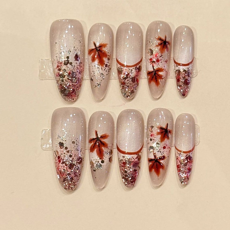 Fall-inspired almond press-ons with hand-painted maple leaves, cascading rose gold glitter & milky nude base - seasonal nail art