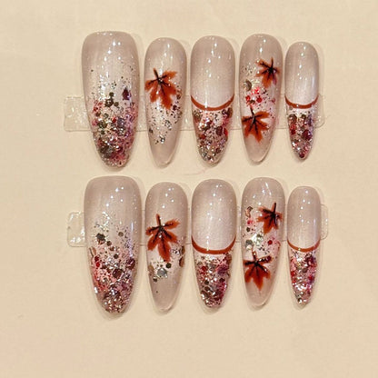 Fall-inspired almond press-ons with hand-painted maple leaves, cascading rose gold glitter & milky nude base - seasonal nail art