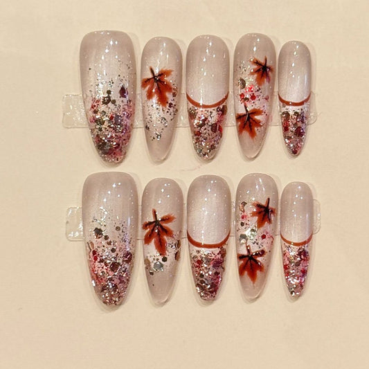 Fall-inspired almond press-ons with hand-painted maple leaves, cascading rose gold glitter & milky nude base - seasonal nail art