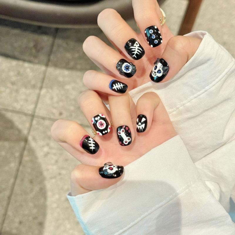 Handcrafted Halloween nails featuring detailed skull motifs, colorful eyeball designs, skeleton patterns - oval short shape for gothic elegance