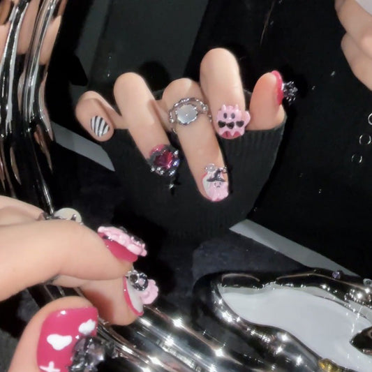 Handcrafted Halloween nails featuring pink skulls, gothic crosses, and stripes - easy DIY application for kawaii gothic look