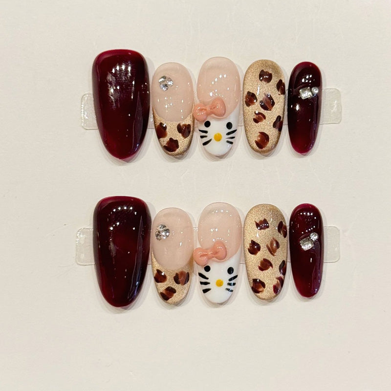 KAPOWNAILS almond nails featuring kawaii design - cute Hello Kitty, brown leopard spots, burgundy shine, gold glitter, handcrafted quality, 10-piece set