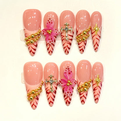 KAPOWNAILS stiletto nails featuring opulent design - delicate pink flower, silver cross, gold beads, red chevron, handcrafted quality, 10-piece luxury set
