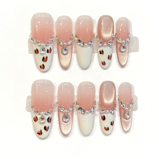 Luxurious oval press-ons with crystal chain jewelry, peachy gradient & playful leopard spots - handcrafted elegant nail art