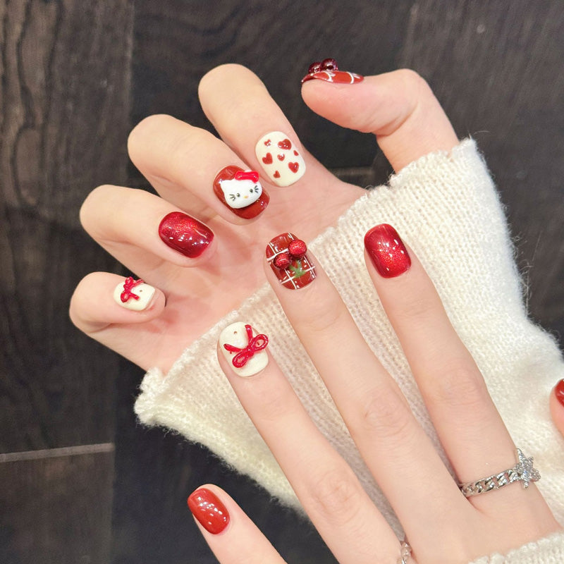 Playful Christmas squoval nails with iconic Hello Kitty, cherry accents & ribbon bows - cute holiday nail collection in red & ivory