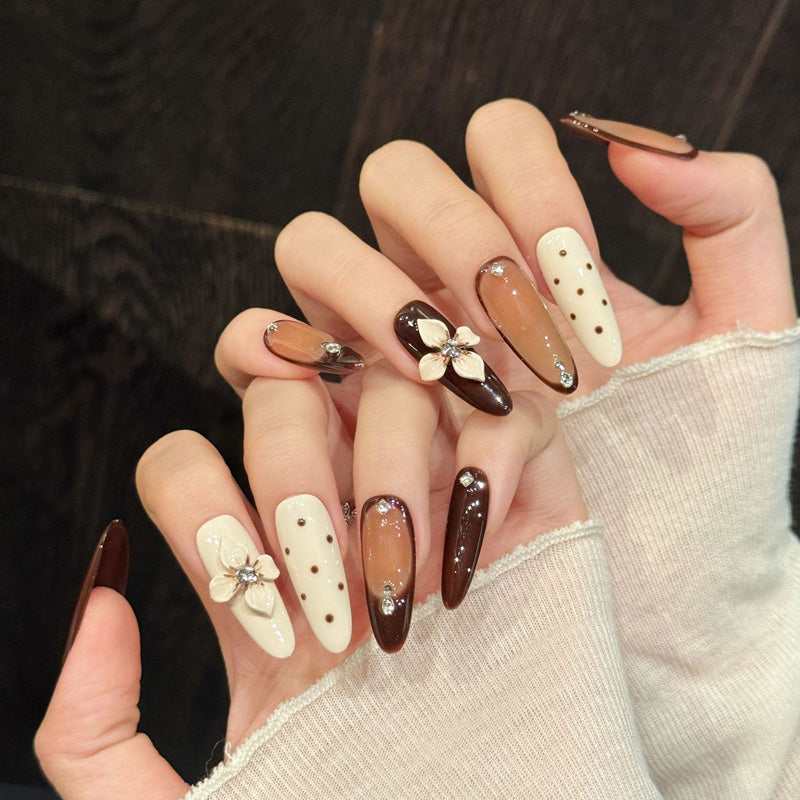 Rich espresso brown almond false nails featuring dimensional floral sculptures, rhinestone accents & creamy neutrals - elegant set