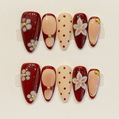 Rich wine-toned almond press-ons with hand-painted cherry blossoms, raised gold studs & peachy nudes - elegant color-blocked design