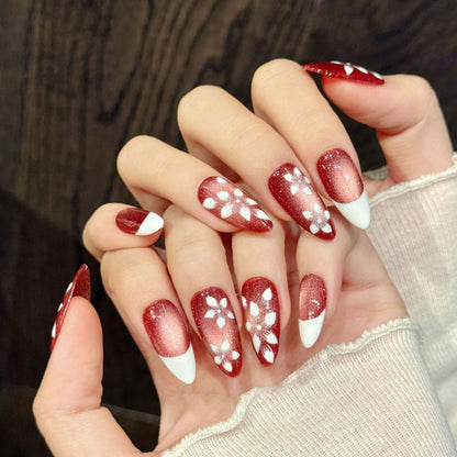 Romantic almond nails with red shimmer gradient, 3D white flowers, gold accents & French tips - perfect for red shimmer white flower gradient elegant charm