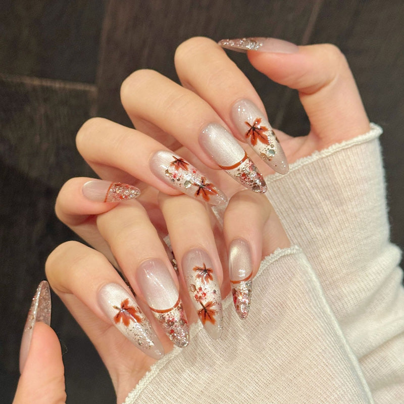 Seasonal almond nails with detailed maple foliage, shimmering rose gold fade & dimensional sparkle - celebrate fall beauty