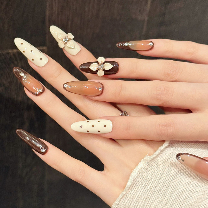 Sophisticated brown-toned almond nails with raised white flowers, sparkling crystals & playful dots - 10-piece reusable collection