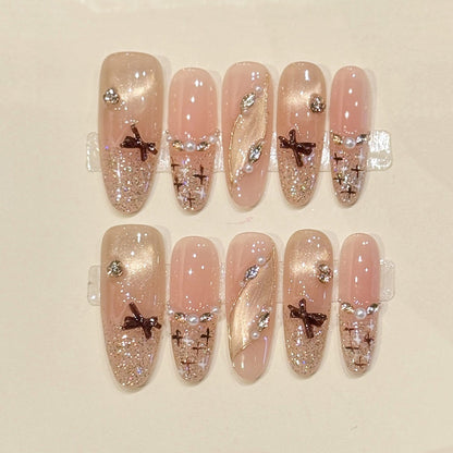 Sophisticated oval press-ons with bronze bow charms, pearl accents & champagne glitter - handcrafted bridal-ready elegant nails