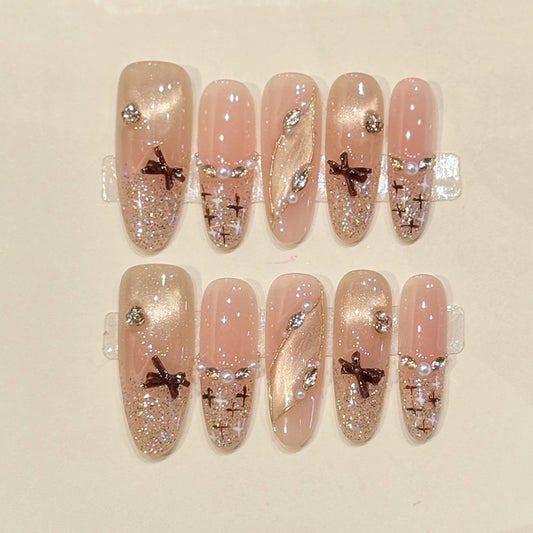 Sophisticated oval press-ons with bronze bow charms, pearl accents & champagne glitter - handcrafted bridal-ready elegant nails
